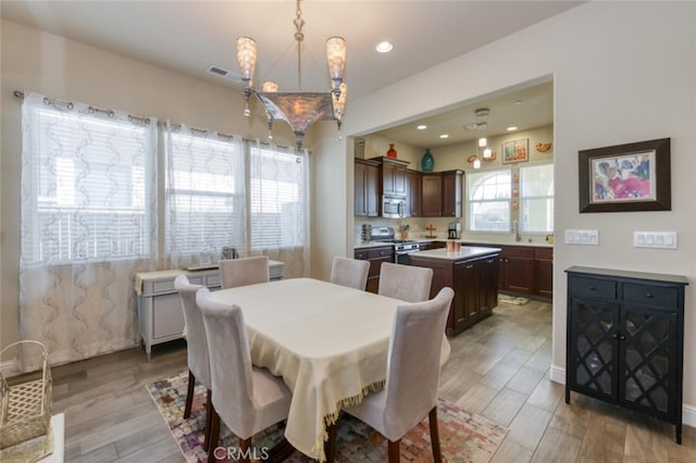 dining space with recessed lighting, light wood-style floors, visible vents, and an inviting chandelier