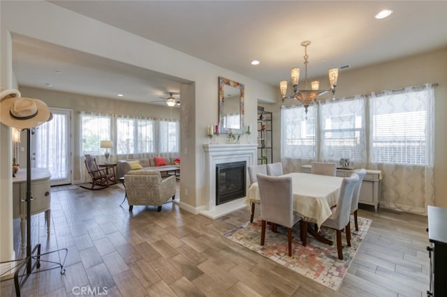 dining room with baseboards, an inviting chandelier, recessed lighting, wood finished floors, and a glass covered fireplace