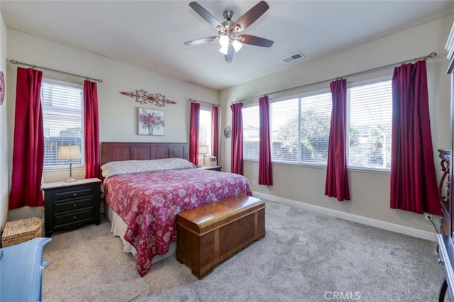 bedroom featuring visible vents, light colored carpet, baseboards, and a ceiling fan