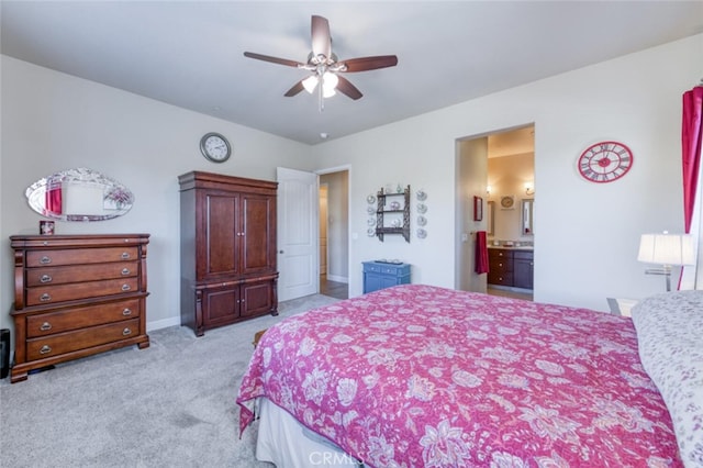 bedroom featuring light carpet, ceiling fan, baseboards, and ensuite bath