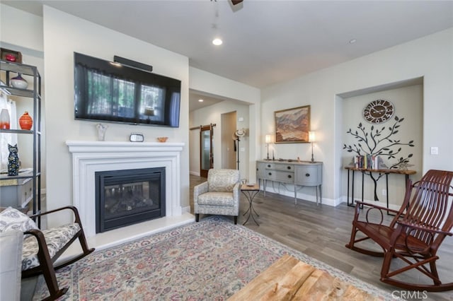 living area with baseboards, ceiling fan, recessed lighting, wood finished floors, and a glass covered fireplace