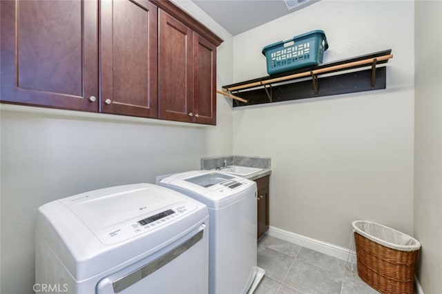 clothes washing area with light tile patterned flooring, a sink, washer and dryer, baseboards, and cabinet space
