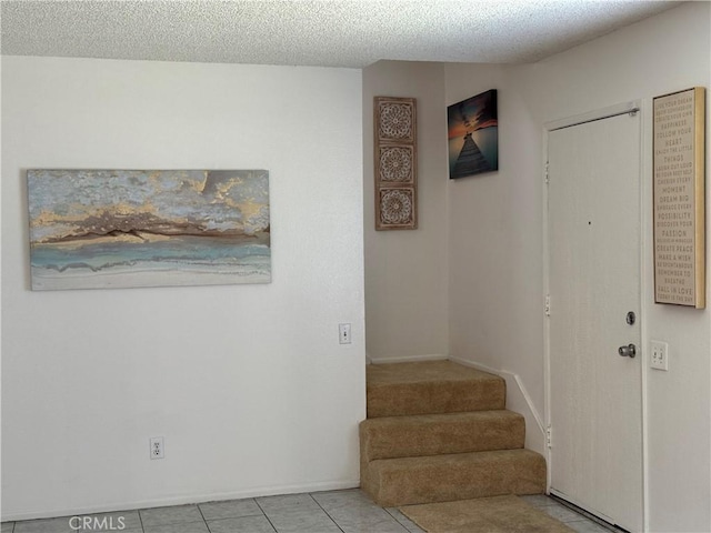 interior space with baseboards, tile patterned flooring, and a textured ceiling