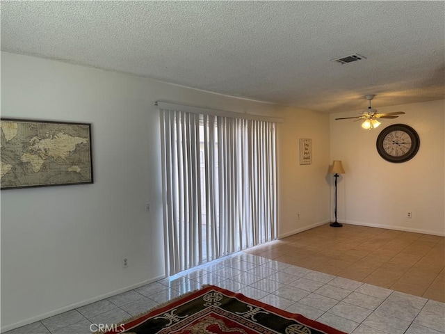spare room featuring tile patterned flooring, visible vents, a textured ceiling, and ceiling fan