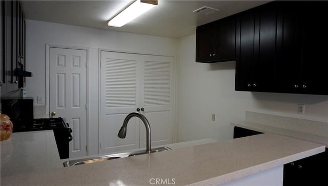 kitchen featuring dark cabinets, a sink, and visible vents