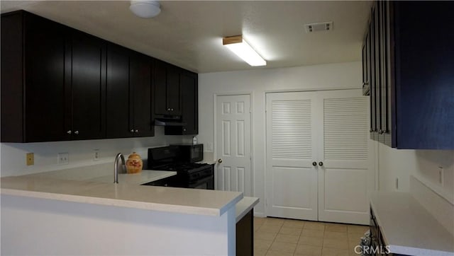kitchen featuring visible vents, dark cabinetry, black appliances, light countertops, and light tile patterned floors