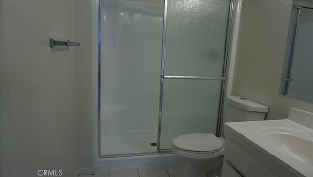 bathroom featuring toilet, vanity, tile patterned flooring, and a stall shower