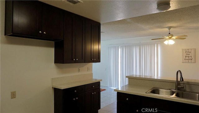 kitchen with a sink, a textured ceiling, visible vents, a ceiling fan, and light countertops