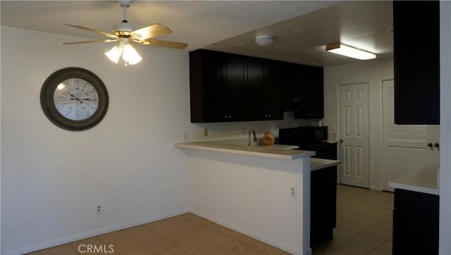 kitchen featuring dark cabinets, light countertops, a ceiling fan, a peninsula, and electric range