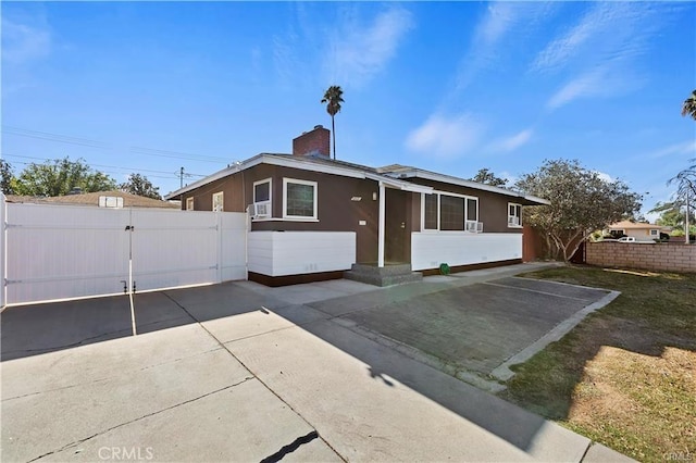 view of front of home with a chimney, fence, and a gate