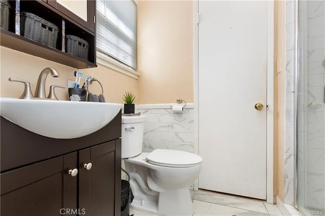 full bath with vanity, a stall shower, a wainscoted wall, toilet, and tile walls