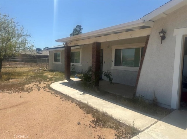 exterior space featuring stucco siding and fence