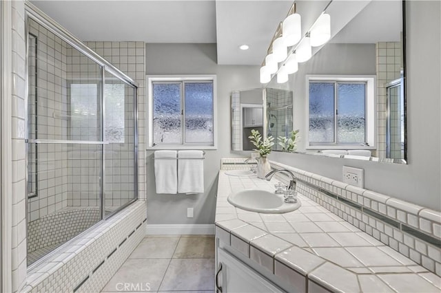 bathroom featuring tile patterned floors, tiled shower, baseboards, and a sink