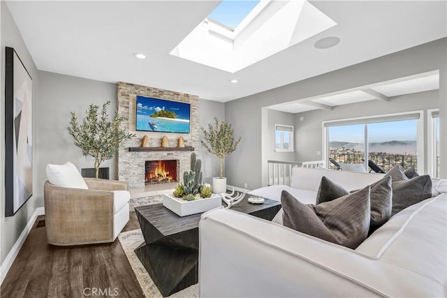 living area featuring baseboards, a fireplace, recessed lighting, wood finished floors, and a skylight