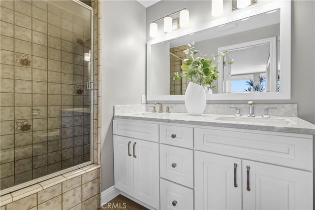 full bathroom with a shower stall, double vanity, and a sink