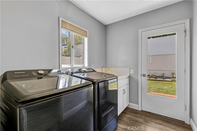 washroom with baseboards, independent washer and dryer, wood finished floors, and cabinet space