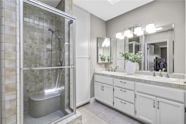 bathroom with a shower stall, tile patterned floors, double vanity, and a sink