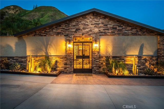 view of exterior entry with a mountain view and stone siding
