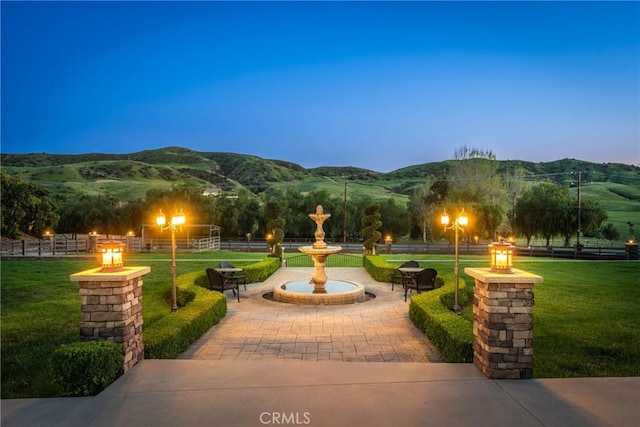 view of property's community with fence, a fire pit, a yard, and a patio