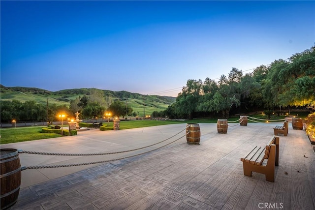 surrounding community with a lawn, a mountain view, and a patio area
