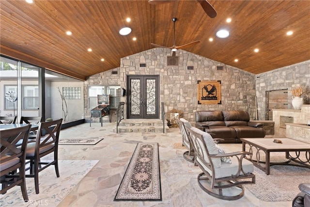 living area featuring lofted ceiling, stone finish flooring, a ceiling fan, and wooden ceiling