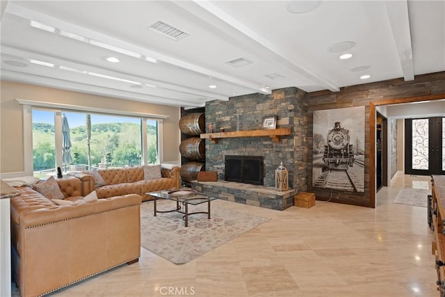 living area with beam ceiling, visible vents, and a fireplace