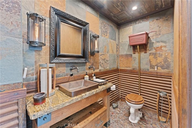 bathroom featuring vanity, toilet, and tile walls