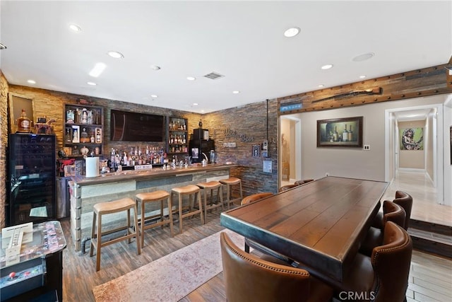 bar featuring recessed lighting, visible vents, a bar, and wood finished floors
