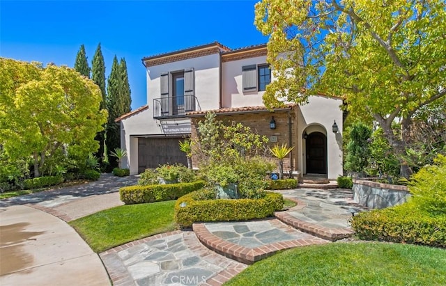 view of front of house featuring driveway, a balcony, a tiled roof, an attached garage, and stucco siding