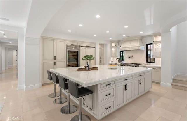 kitchen featuring decorative backsplash, stainless steel built in fridge, recessed lighting, and premium range hood