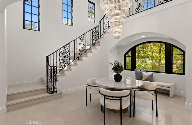 tiled dining room featuring a towering ceiling, arched walkways, and plenty of natural light