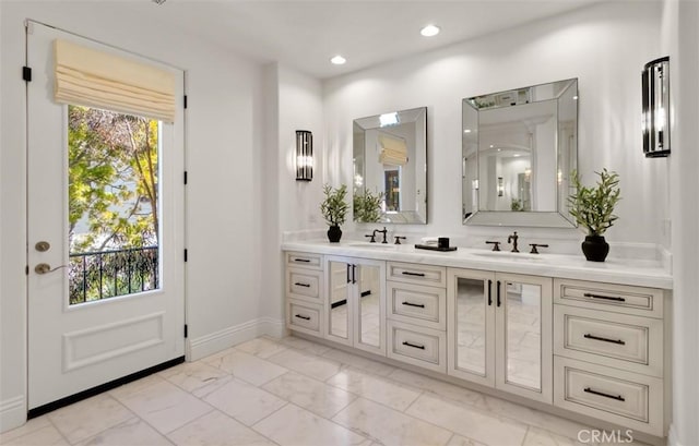 bathroom with baseboards, a sink, double vanity, and marble finish floor