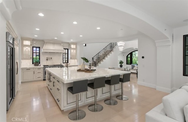 kitchen featuring recessed lighting, light tile patterned floors, high end appliances, custom exhaust hood, and open floor plan
