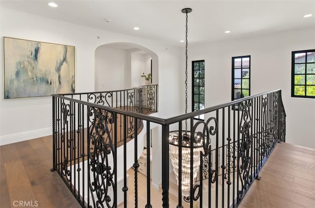 hall featuring baseboards, recessed lighting, wood finished floors, and an upstairs landing