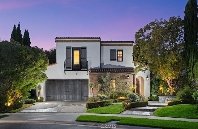 mediterranean / spanish home featuring concrete driveway, a balcony, a tiled roof, stucco siding, and a garage