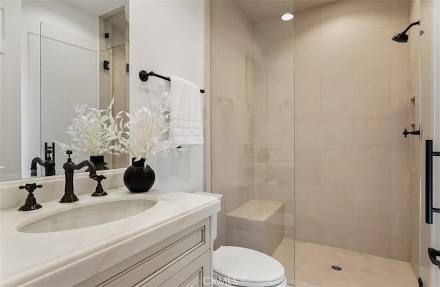 full bath featuring tiled shower, toilet, and vanity