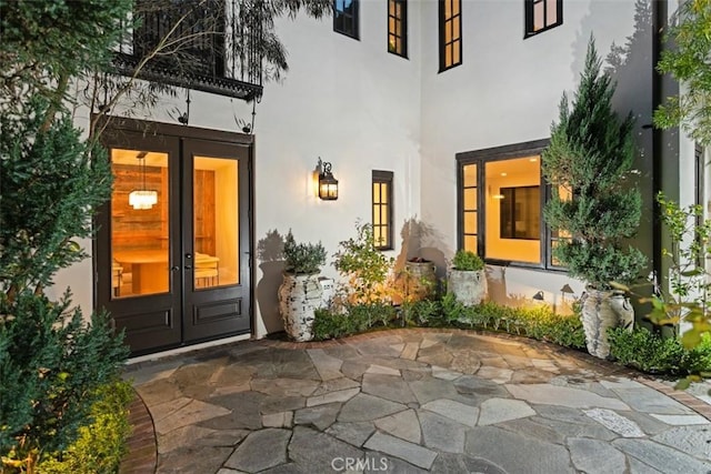 view of exterior entry featuring stucco siding, french doors, and a patio area