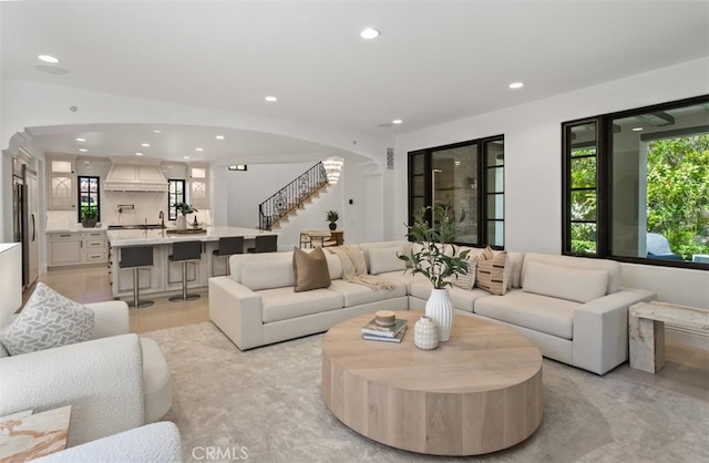 living area with stairway, recessed lighting, and arched walkways