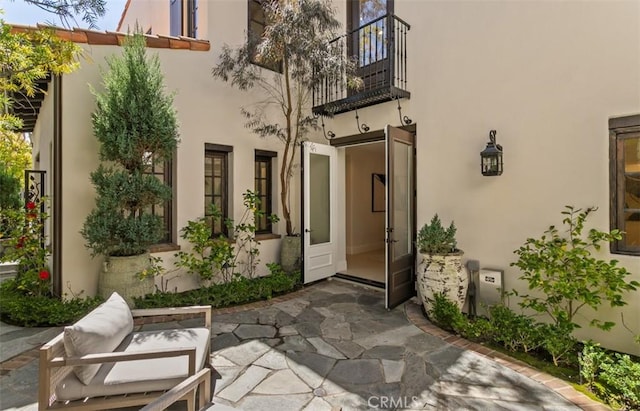 entrance to property featuring a patio, stucco siding, and a balcony