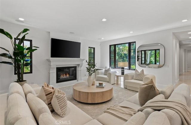living room featuring a glass covered fireplace, recessed lighting, and baseboards