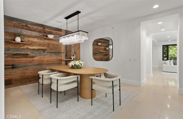 dining area with recessed lighting, a chandelier, light tile patterned floors, wooden walls, and baseboards