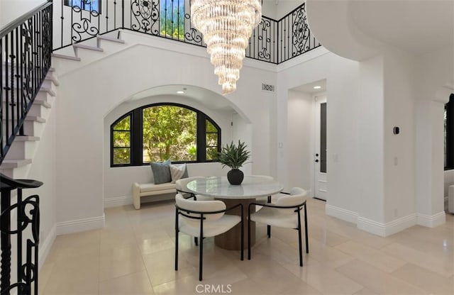 tiled dining space featuring a chandelier, stairs, visible vents, a towering ceiling, and arched walkways