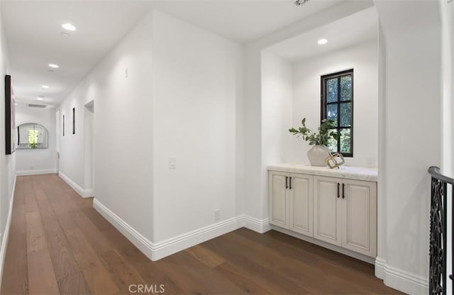 corridor featuring dark wood-style floors, recessed lighting, a wealth of natural light, and baseboards