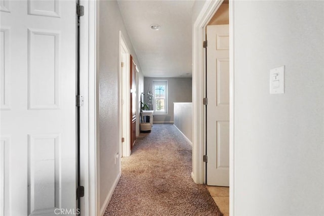 corridor featuring light carpet and baseboards
