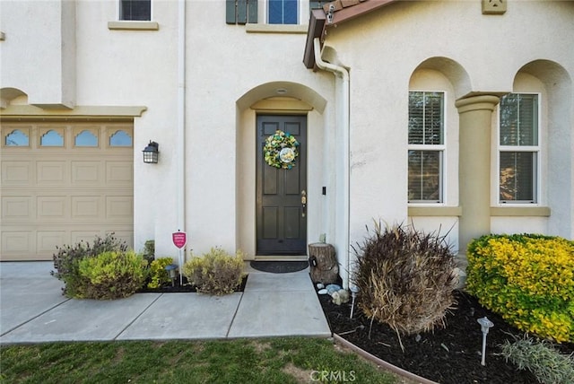 doorway to property with a garage and stucco siding