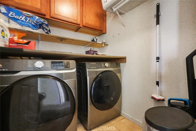 laundry room with washer and clothes dryer, light tile patterned flooring, and cabinet space