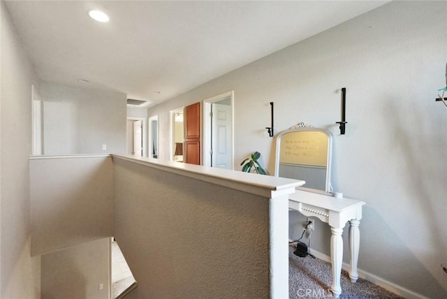 corridor with carpet, visible vents, and baseboards