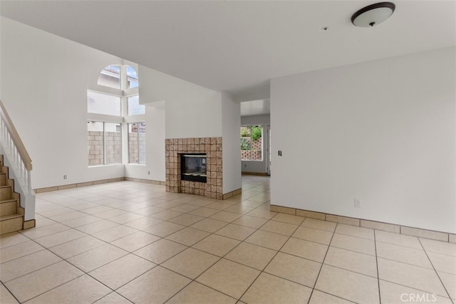 15767 San Roque Rd, Fontana, CA 92337 - unfurnished living room with light tile patterned floors, stairs, baseboards, and a tiled fireplace