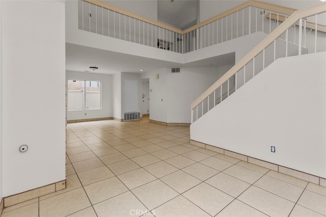 15767 San Roque Rd, Fontana, CA 92337 - unfurnished living room featuring a high ceiling, stairway, tile patterned flooring, and baseboards