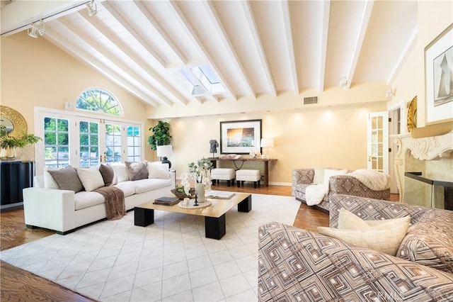 living room with a high end fireplace, visible vents, beamed ceiling, and track lighting
